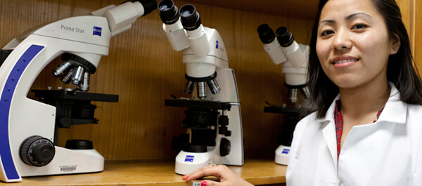Veterinary Technology: student next to a microscope for looking at samples